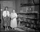 Two women with display of baskets and other artifacts, 6/25/61, #39437_1