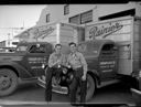 Two men with beer bottles and Rainier Beer trucks, 7/1948, #24395_1