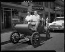 Two men in 1902 Oldsmobile in front of Jones Photo Co., 8/1/1958, #33404_1