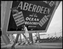 Painting out Grays Harbor Chamber of Commerce sign on Wishkah Bridge, 7/13/1964, #46695_1