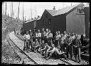 Group of loggers on railroad tracks with camp buildings, circa 1915, #G0568_1