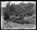 Group picnicking on logs at beach, circa 1907, #G1023_1