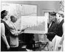 Four people viewing Washington State teachers' pay comparison chart, 9/7/1956, #31496_1